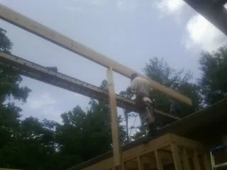Carpenter setting a ridge beam over a new addition frame — Ice Dam Removal by Roofing Brothers in Maidsville