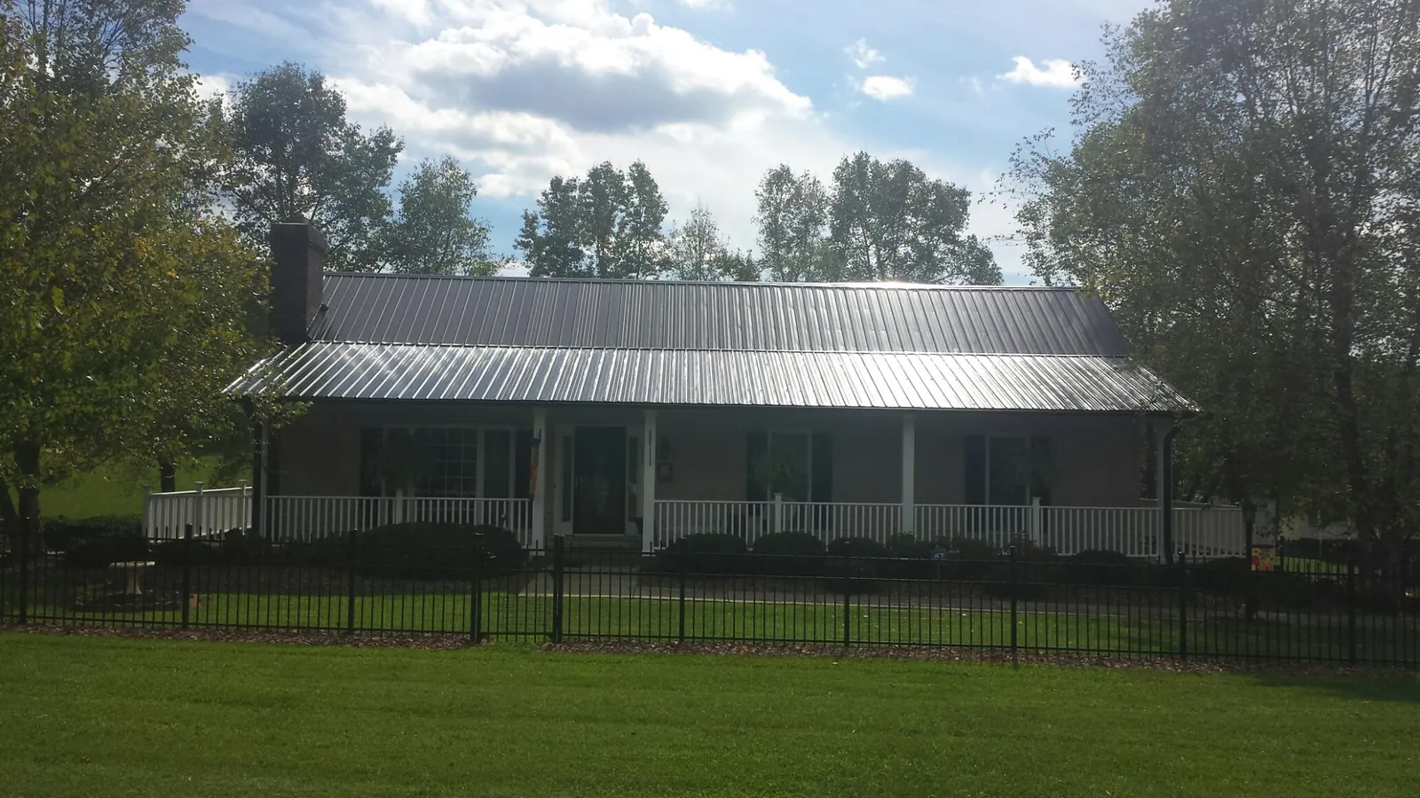 Gray metal roof on a brick ranch with a full width front porch — Gutter Guard Installation work by our crew in Maidsville