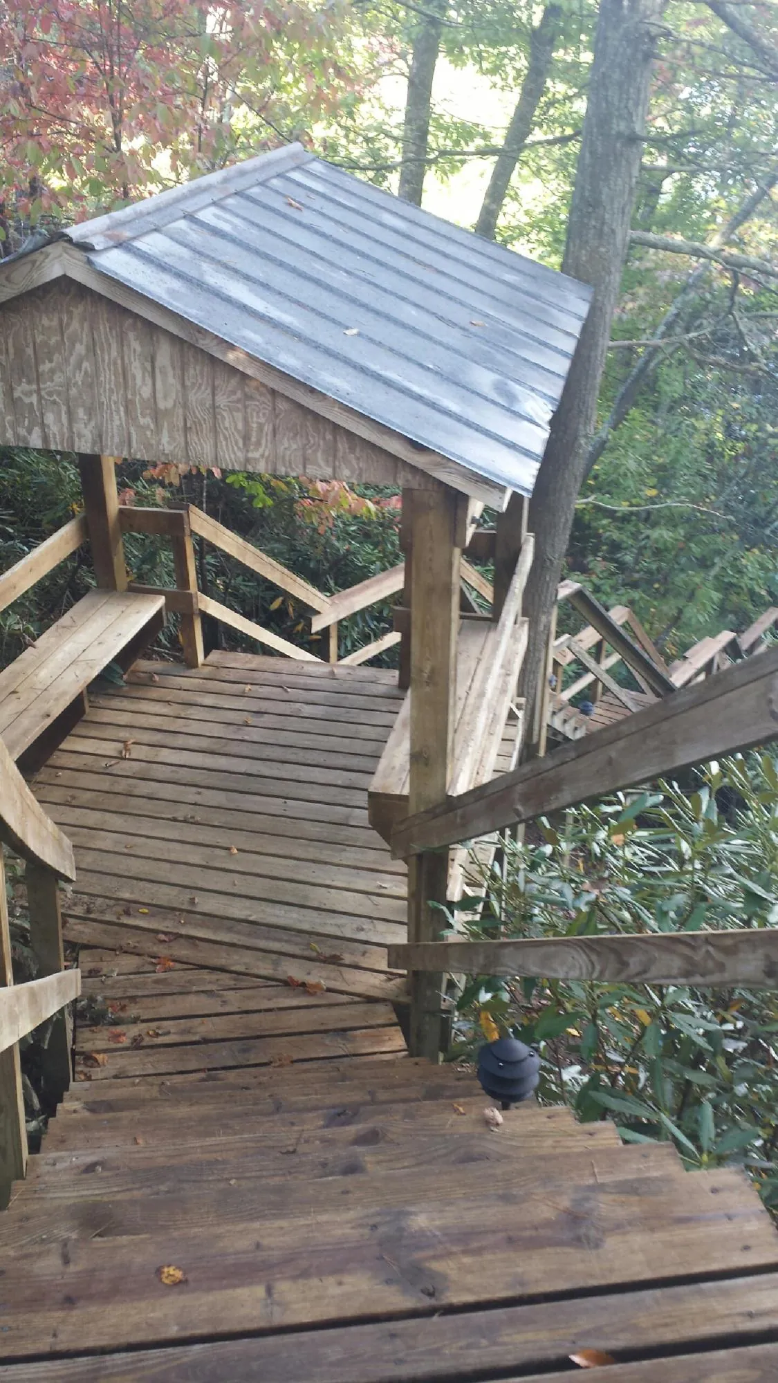 Metal roofed shelter over wooden steps on a wooded walkway — Skylight Repair & Installation work by our crew in Maidsville