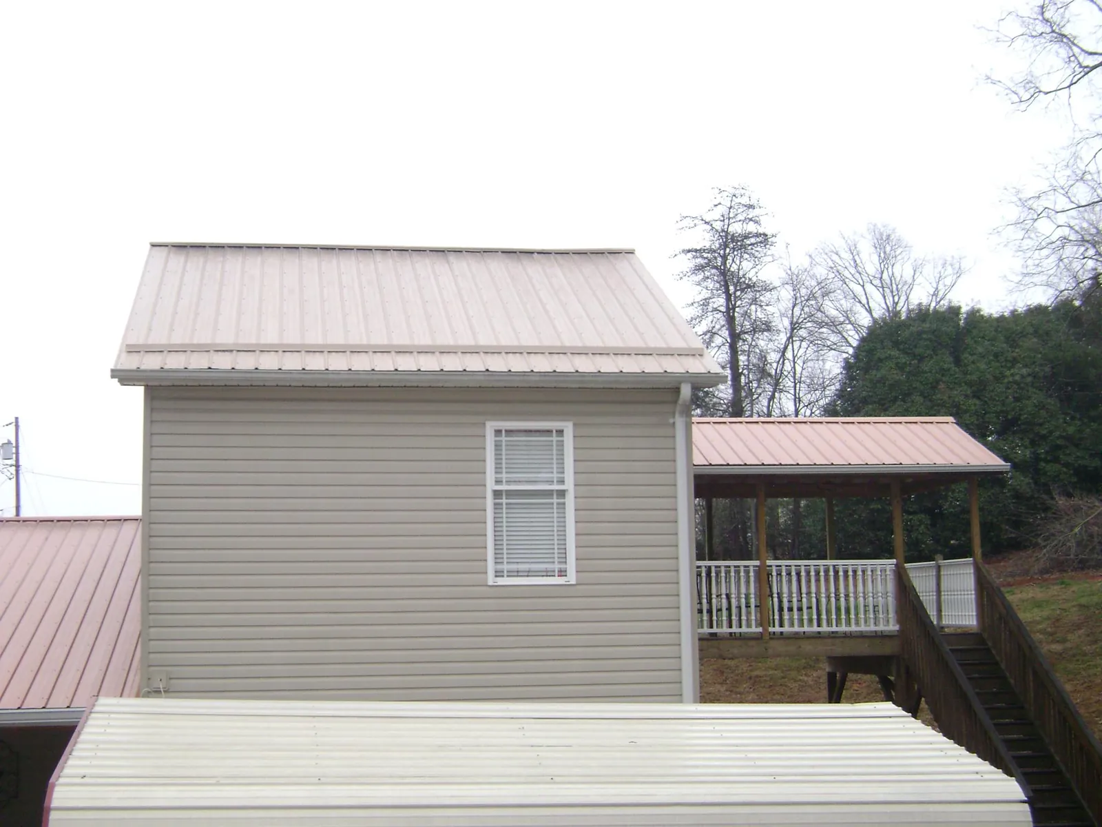 Tan metal roofs on a two story addition and attached porch, from a Roof Replacement job in Maidsville
