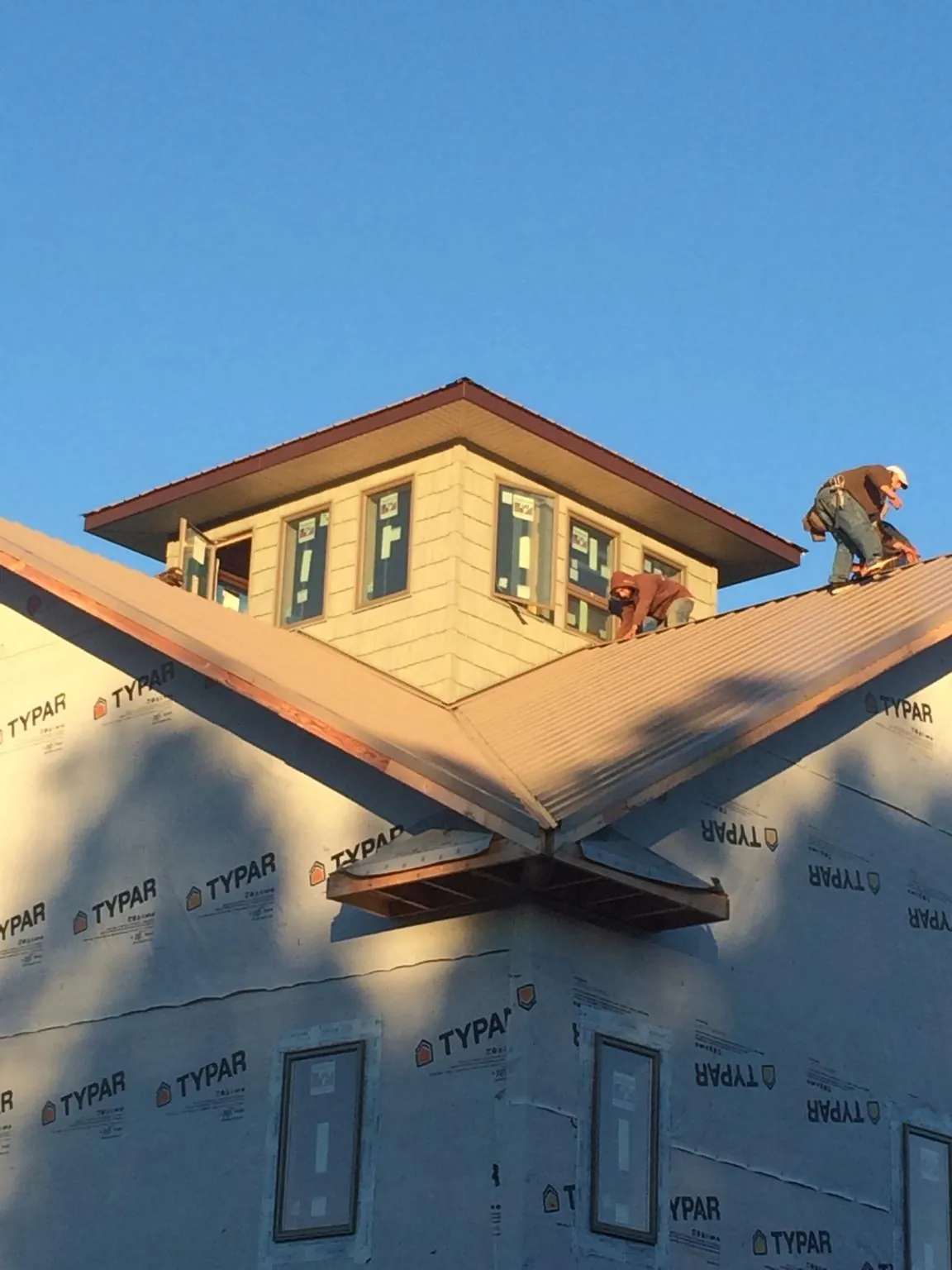Roofers working around a rooftop cupola on a new metal roof at sunset — Roof Waterproofing in Maidsville by Roofing Brothers